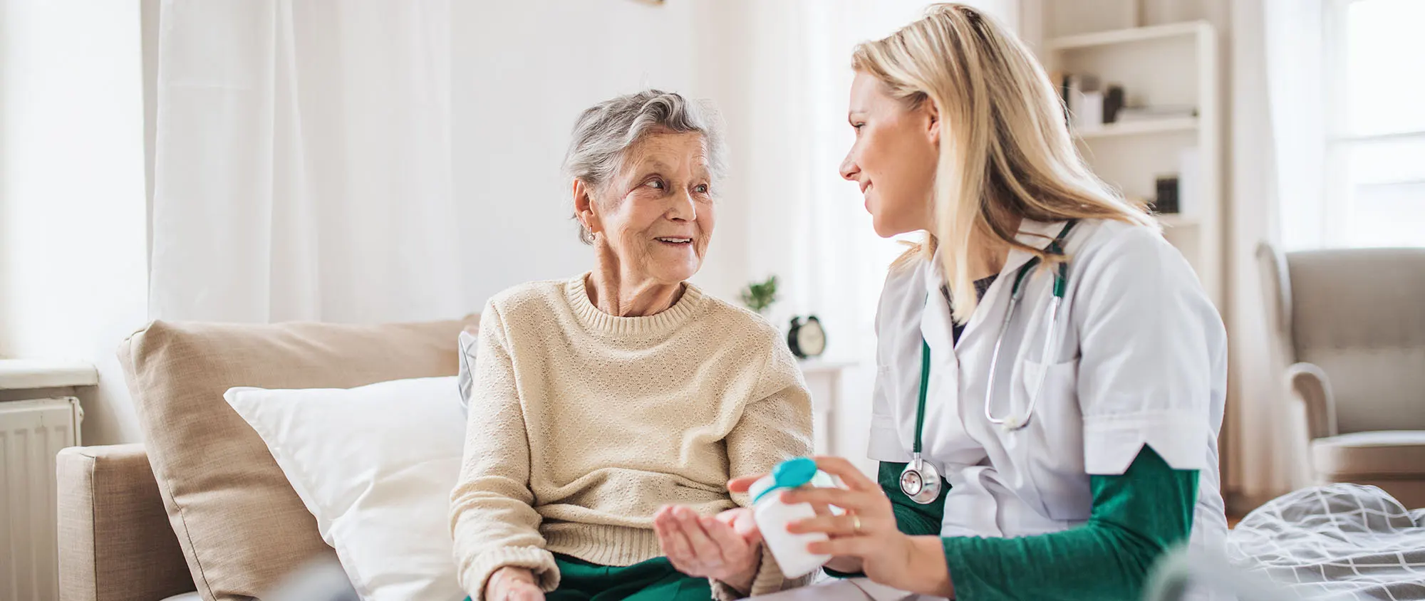 Dame auf der Couch, die von einer Pflegerin betreut wird