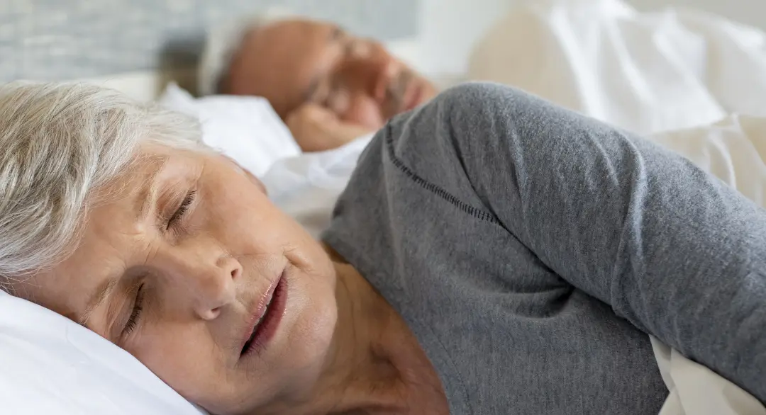 Seniorin liegt im Bett und schläft.